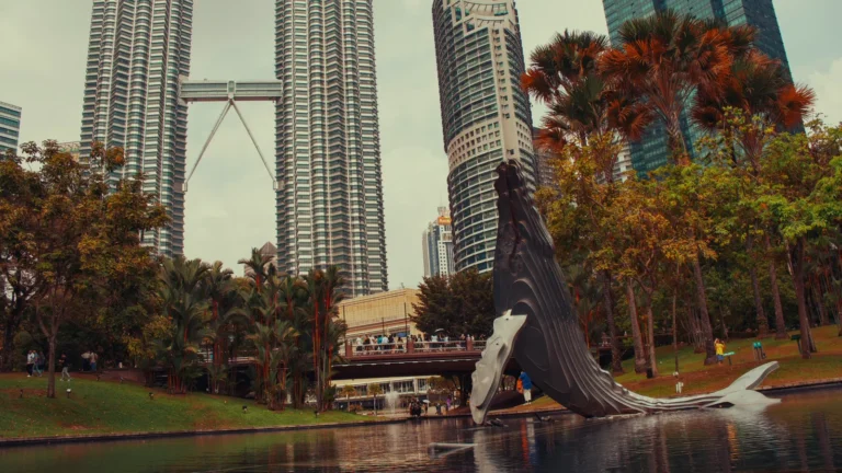 Twin towers above trees and park sculpture in Kuala Lumpur, Malaysia