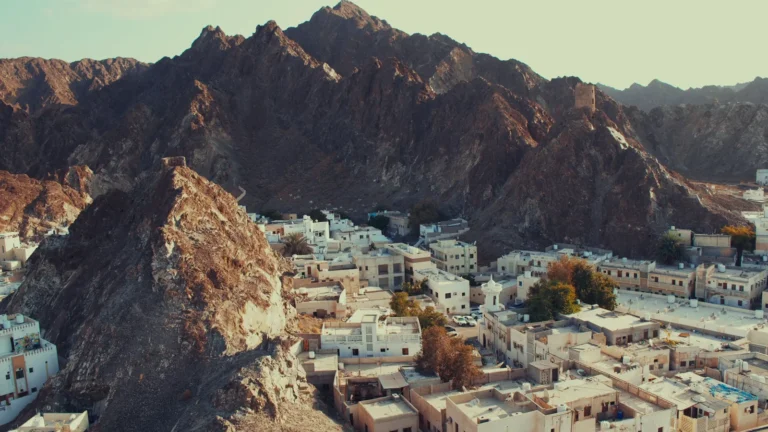 Whitewashed town below jagged mountains in Oman