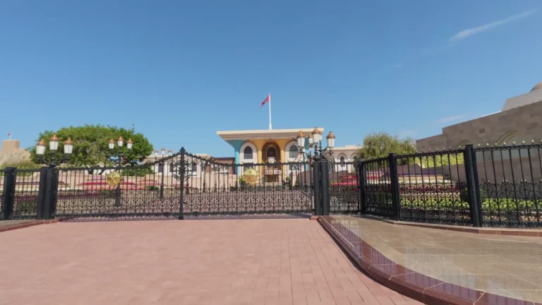 Ornate palace gates across a paved square in Oman