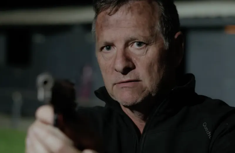 Andy Blithe film still, close-up holding a gun