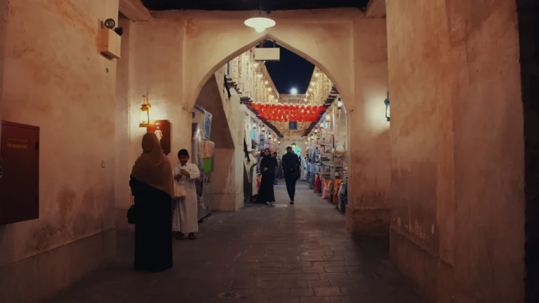 People walking through an arched souq passage in Qatar