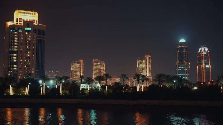 City towers lit up at night across the water in Qatar