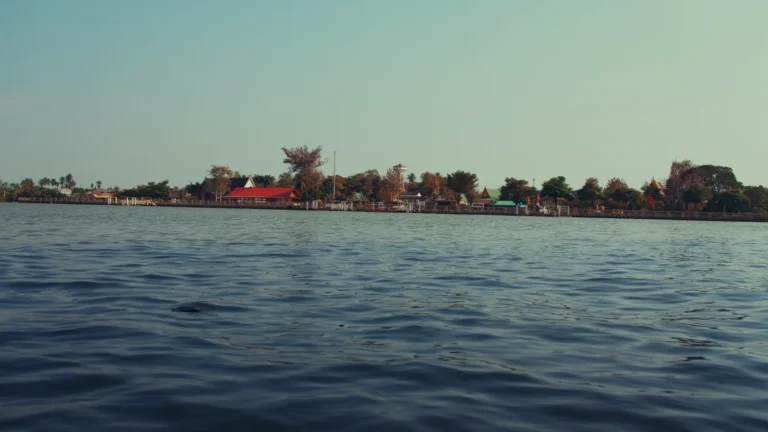 Wide river with temples on the far bank in Thailand