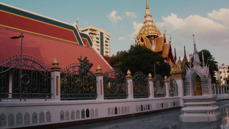 Temple buildings and spires behind a white wall in Thailand